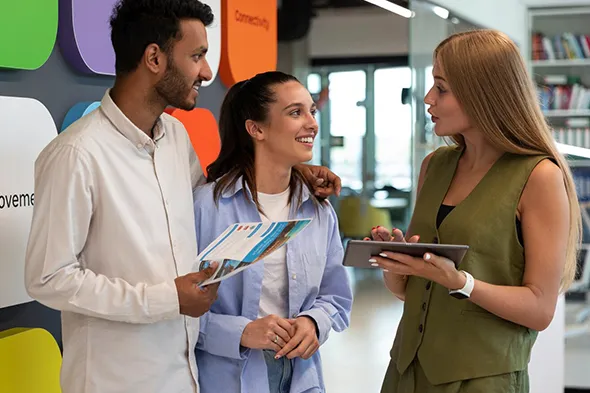 Travel agent assisting a smiling couple with booking their dream vacation package.