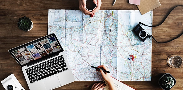 Travel agent discussing with client about travel plans at desk with a map.