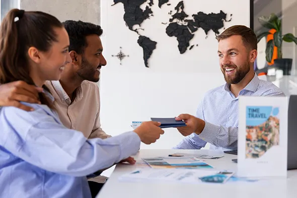 Smiling travel agent handing flight tickets to a happy couple planning their luxury vacation.