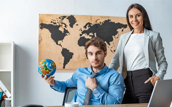 Friendly travel agents with an Earth globe in a modern office, showcasing expert vacation planning services.