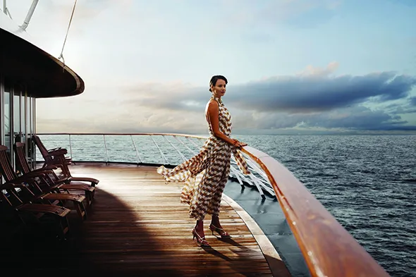 Woman standing on a luxury cruise with a beautiful sunset view.